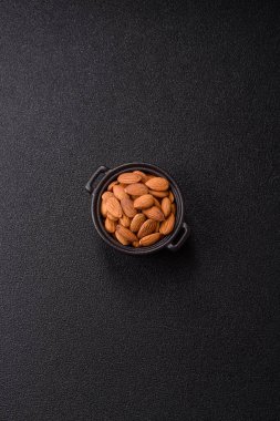 Koyu beton arka planda kavrulmuş ya da soyulmuş bademler.