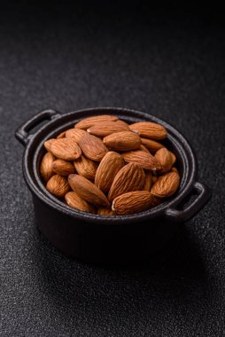 Koyu beton arka planda kavrulmuş ya da soyulmuş bademler.