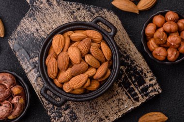 Koyu beton arka planda kavrulmuş ya da soyulmuş bademler.