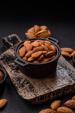 Koyu beton arka planda kavrulmuş ya da soyulmuş bademler.