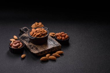 Koyu beton arka planda kavrulmuş ya da soyulmuş bademler.