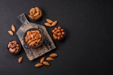 Koyu beton arka planda kavrulmuş ya da soyulmuş bademler.