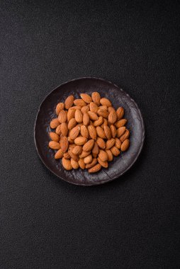 Koyu beton arka planda kavrulmuş ya da soyulmuş bademler.