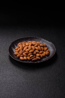 Koyu beton arka planda kavrulmuş ya da soyulmuş bademler.