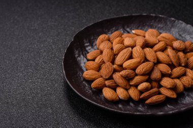 Koyu beton arka planda kavrulmuş ya da soyulmuş bademler.