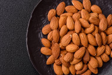 Koyu beton arka planda kavrulmuş ya da soyulmuş bademler.