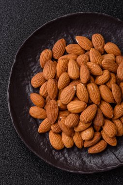 Koyu beton arka planda kavrulmuş ya da soyulmuş bademler.