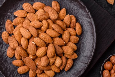 Koyu beton arka planda kavrulmuş ya da soyulmuş bademler.