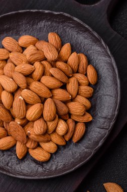 Koyu beton arka planda kavrulmuş ya da soyulmuş bademler.