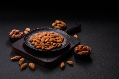 Koyu beton arka planda kavrulmuş ya da soyulmuş bademler.