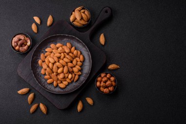 Koyu beton arka planda kavrulmuş ya da soyulmuş bademler.