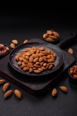 Koyu beton arka planda kavrulmuş ya da soyulmuş bademler.
