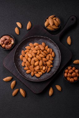 Koyu beton arka planda kavrulmuş ya da soyulmuş bademler.