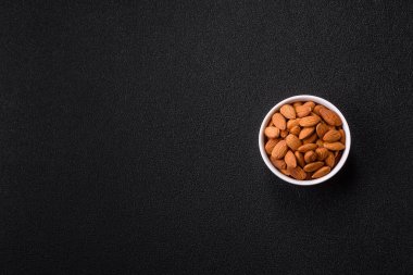 Koyu beton arka planda kavrulmuş ya da soyulmuş bademler.