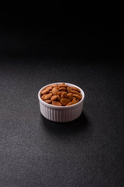 Koyu beton arka planda kavrulmuş ya da soyulmuş bademler.