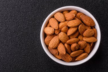 Koyu beton arka planda kavrulmuş ya da soyulmuş bademler.