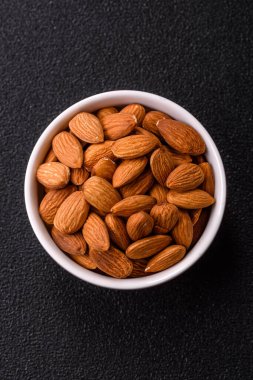 Koyu beton arka planda kavrulmuş ya da soyulmuş bademler.