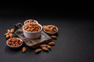 Koyu beton arka planda kavrulmuş ya da soyulmuş bademler.