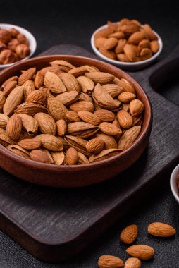 Kavrulmuş ya da çiğ badem fıstığı kabukta koyu beton arka planda.