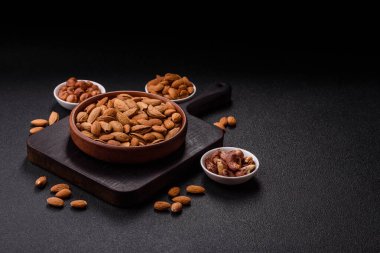 Kavrulmuş ya da çiğ badem fıstığı kabukta koyu beton arka planda.