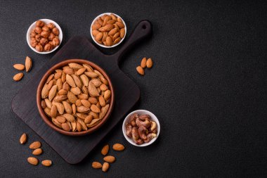 Kavrulmuş ya da çiğ badem fıstığı kabukta koyu beton arka planda.