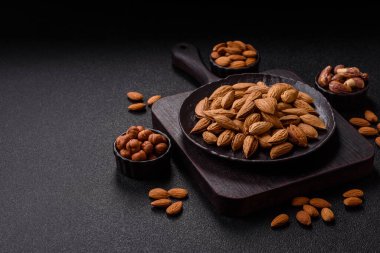 Kavrulmuş ya da çiğ badem fıstığı kabukta koyu beton arka planda.