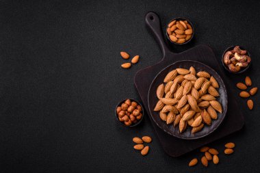 Kavrulmuş ya da çiğ badem fıstığı kabukta koyu beton arka planda.