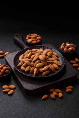 Kavrulmuş ya da çiğ badem fıstığı kabukta koyu beton arka planda.