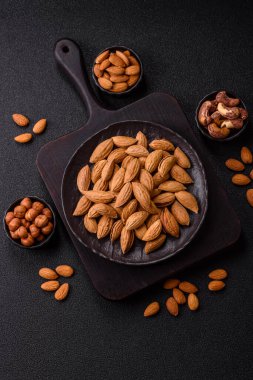 Kavrulmuş ya da çiğ badem fıstığı kabukta koyu beton arka planda.