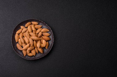 Kavrulmuş ya da çiğ badem fıstığı kabukta koyu beton arka planda.