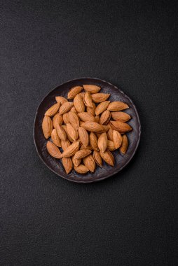 Kavrulmuş ya da çiğ badem fıstığı kabukta koyu beton arka planda.