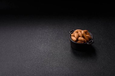 Kavrulmuş ya da çiğ badem fıstığı kabukta koyu beton arka planda.