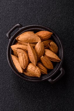 Kavrulmuş ya da çiğ badem fıstığı kabukta koyu beton arka planda.