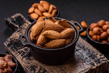 Kavrulmuş ya da çiğ badem fıstığı kabukta koyu beton arka planda.