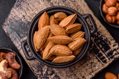 Kavrulmuş ya da çiğ badem fıstığı kabukta koyu beton arka planda.