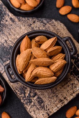 Kavrulmuş ya da çiğ badem fıstığı kabukta koyu beton arka planda.