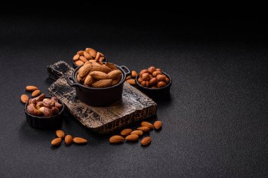 Kavrulmuş ya da çiğ badem fıstığı kabukta koyu beton arka planda.