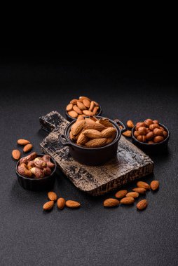 Kavrulmuş ya da çiğ badem fıstığı kabukta koyu beton arka planda.