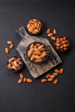 Kavrulmuş ya da çiğ badem fıstığı kabukta koyu beton arka planda.