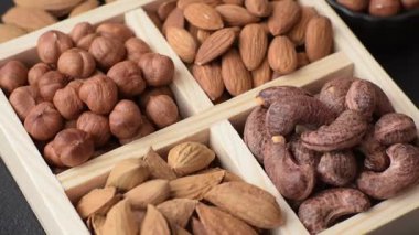 İçinde fındık bademleri, kabuklu bademler, cevizler, fındıklar olan tahta kutu.