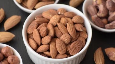 Koyu beton arka planda kavrulmuş ya da soyulmuş bademler.