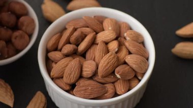 Koyu beton arka planda kavrulmuş ya da soyulmuş bademler.
