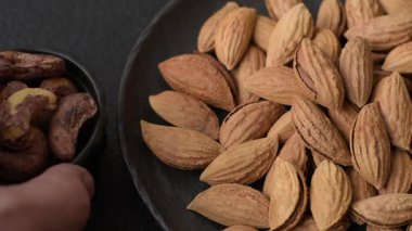 Kavrulmuş ya da çiğ badem fıstığı kabukta koyu beton arka planda.