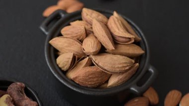 Kavrulmuş ya da çiğ badem fıstığı kabukta koyu beton arka planda.