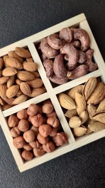 İçinde fındık bademleri, kabuklu bademler, cevizler, fındıklar olan tahta kutu.