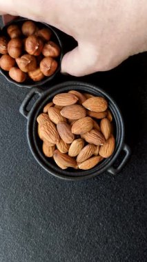 Koyu beton arka planda kavrulmuş ya da soyulmuş bademler.