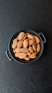 Koyu beton arka planda kavrulmuş ya da soyulmuş bademler.