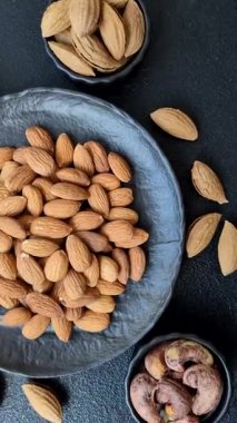 Koyu beton arka planda kavrulmuş ya da soyulmuş bademler.