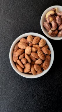 Koyu beton arka planda kavrulmuş ya da soyulmuş bademler.