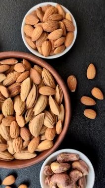 Kavrulmuş ya da çiğ badem fıstığı kabukta koyu beton arka planda.